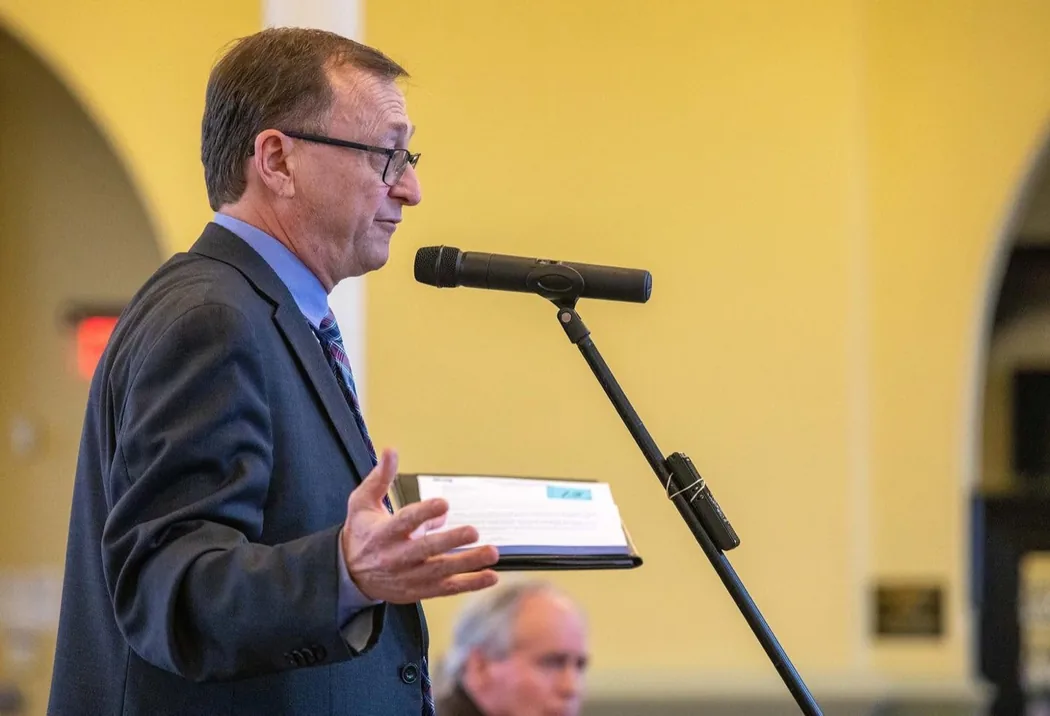 Mike Wallace delivering a talk at a microphone during a community event
