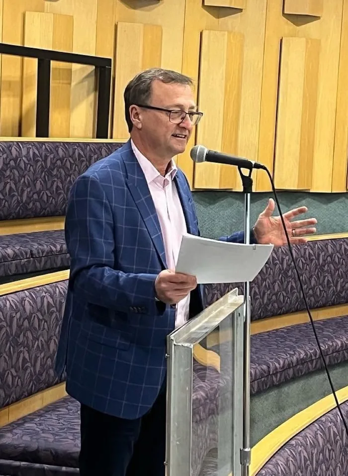 Mike Wallace speaking from a lectern in a council chamber
